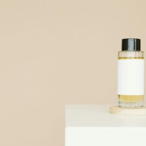 A sleek cosmetic bottle with blank label on a clean white platform against a neutral background.